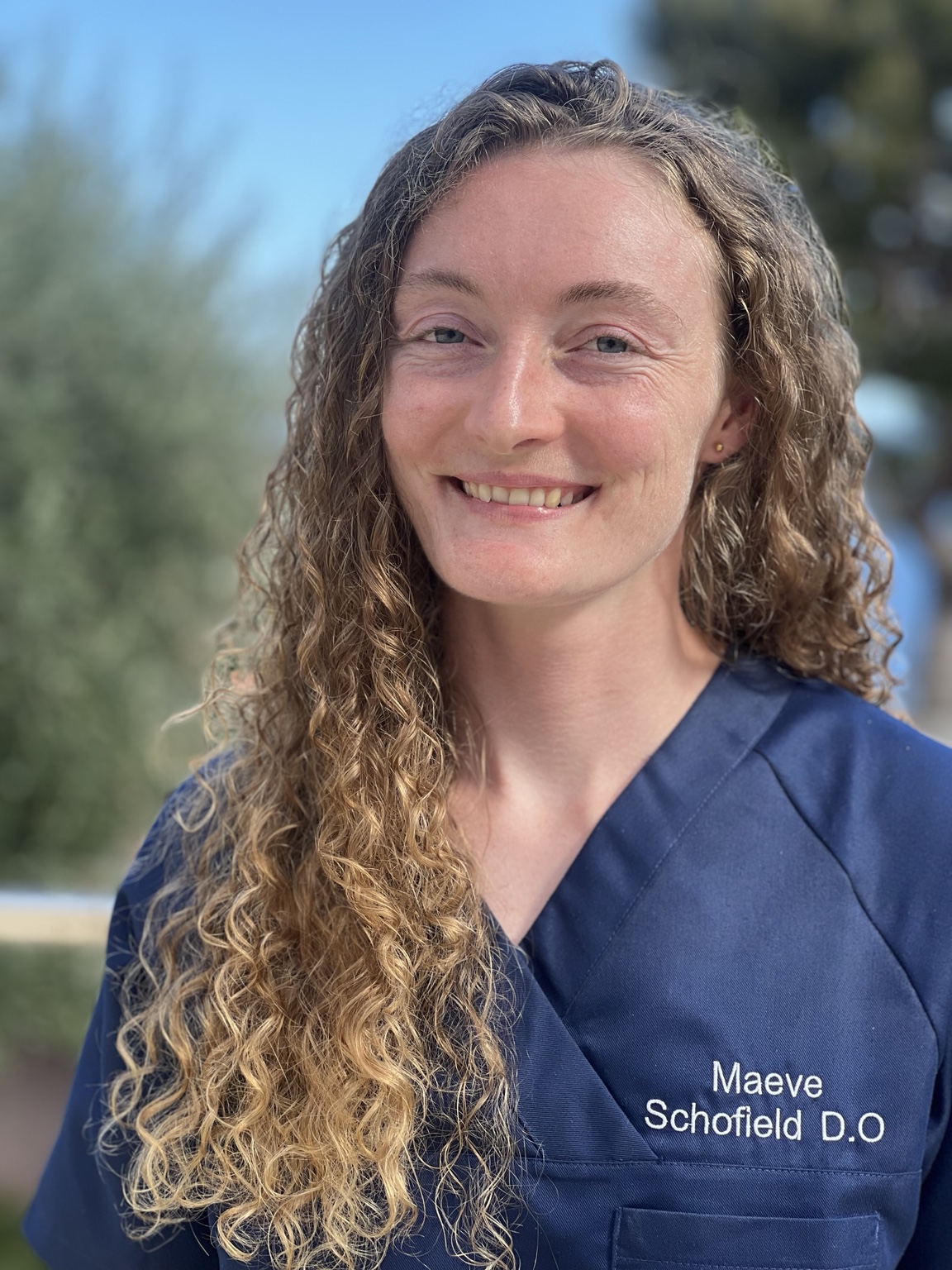 Maeve Schofield, ostéopathe D.O., souriante en tenue professionnelle bleue